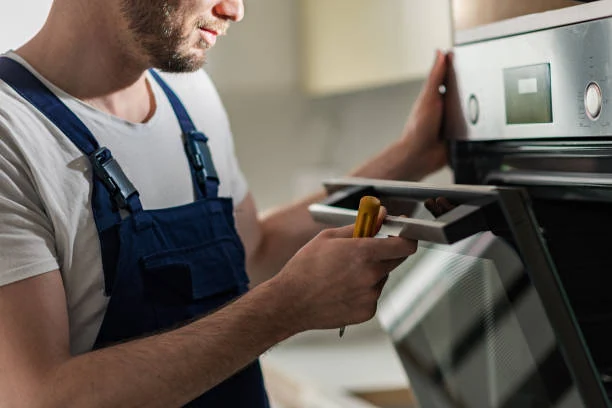 Technician inspecting an oven control panel with a screwdriver