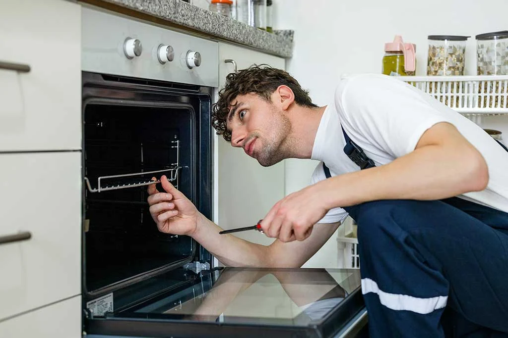 Technician inspecting the interior of a built-in kitchen oven