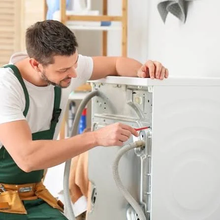 Technician inspecting the rear connections of a washing machine