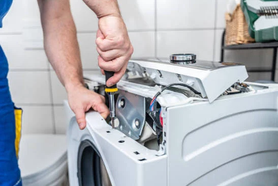 Technician repairing the opened top control assembly of a washing machine